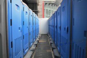Home 10 A series of blue portable toilets aligned at an outdoor construction site.