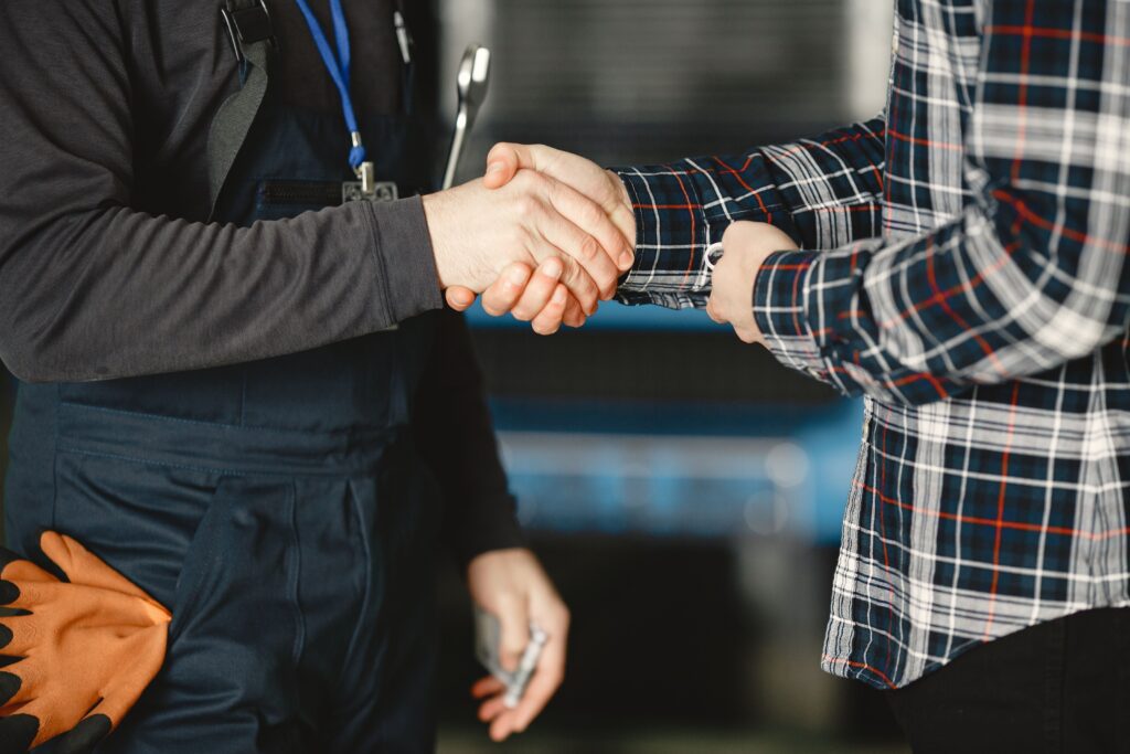 How to Choose a Dumpster Rental Company 2 Close-up of a handshake between workers in a workshop, symbolizing business agreement and teamwork.